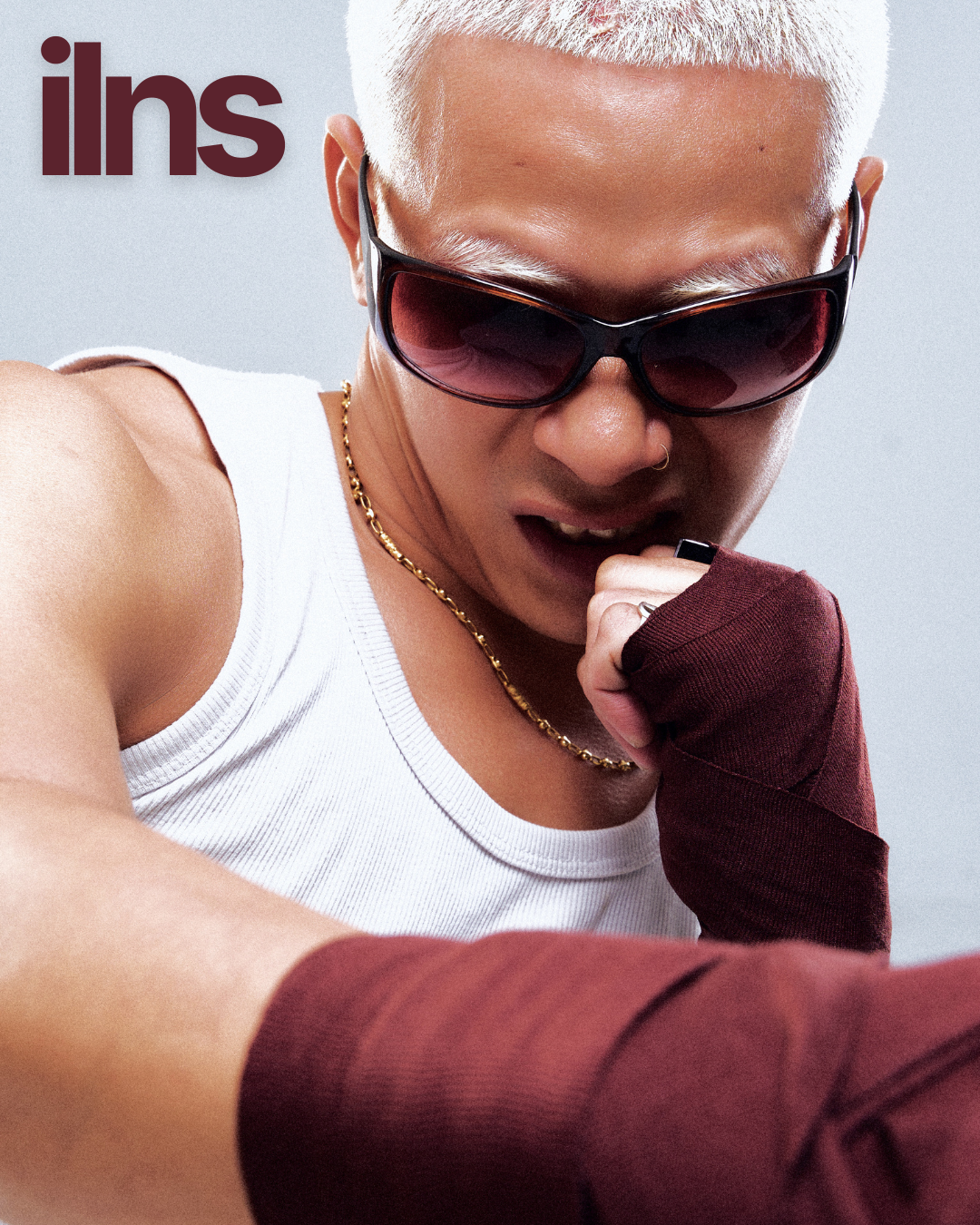 Person wearing sunglasses and a white tank top with a blurred background