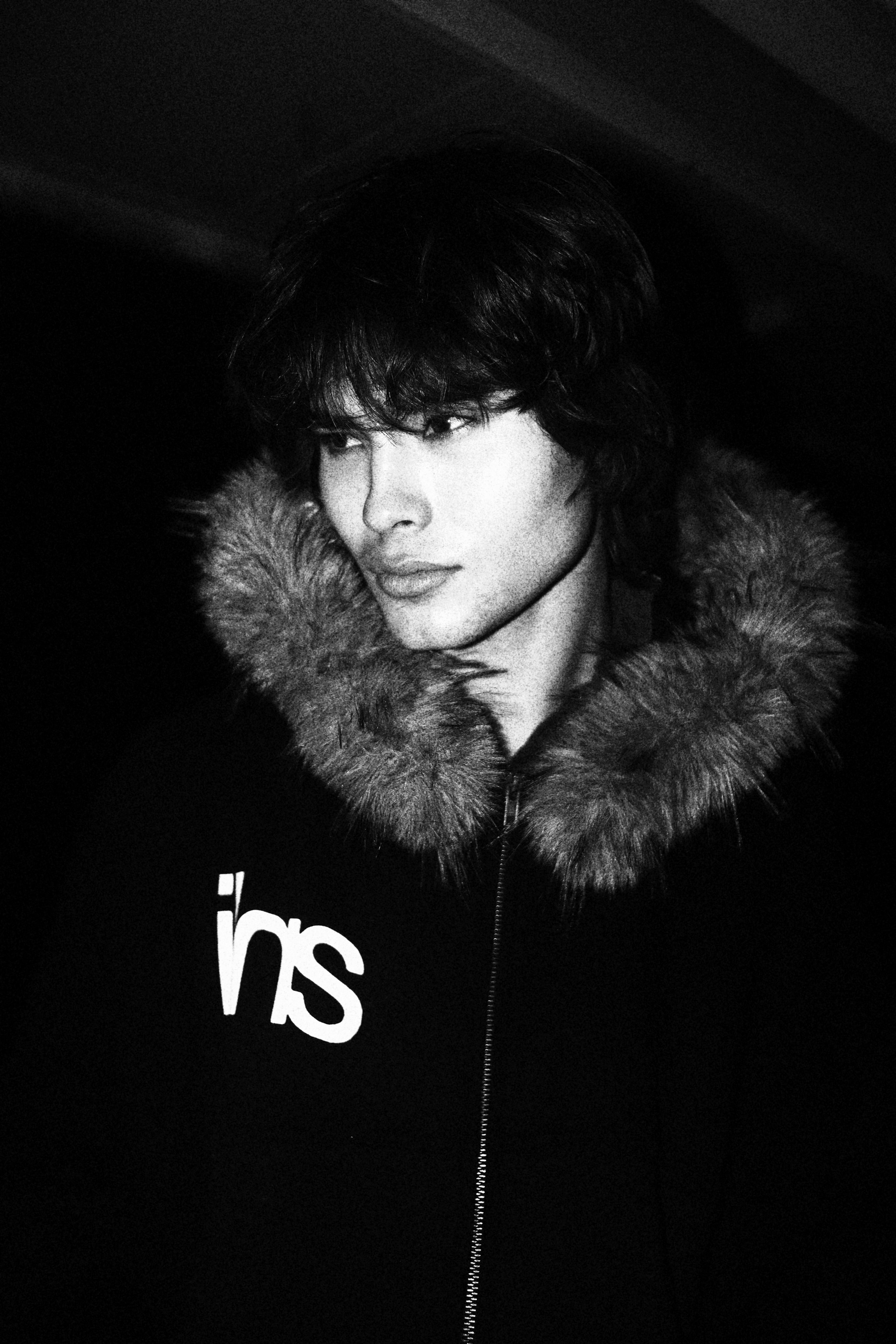 Person wearing a dark hoodie with a fur-lined hood, black and white photo.